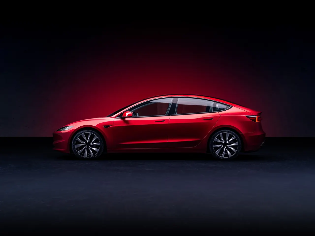 Tesla Model 3 rojo de perfil sobre fondo oscuro con un halo de luz roja
